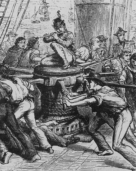 Musician plays a flute to lead the capstan shanty while crew push the bars
