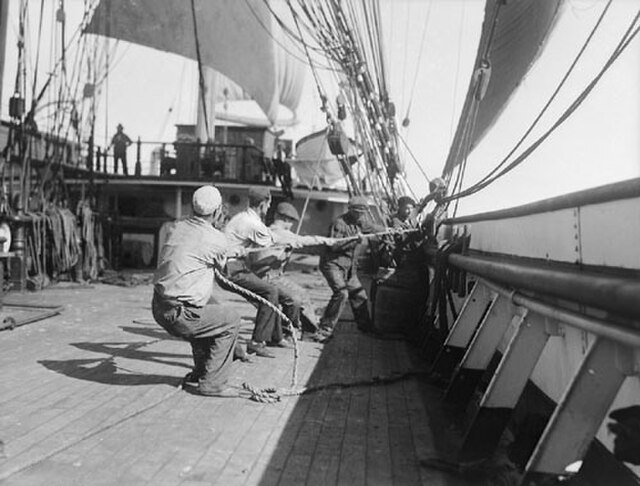 Sailors hauling on the halyards of a square-rigged sailing ship — the kind of heavy work Blow the Man Down was sung to coordinate
